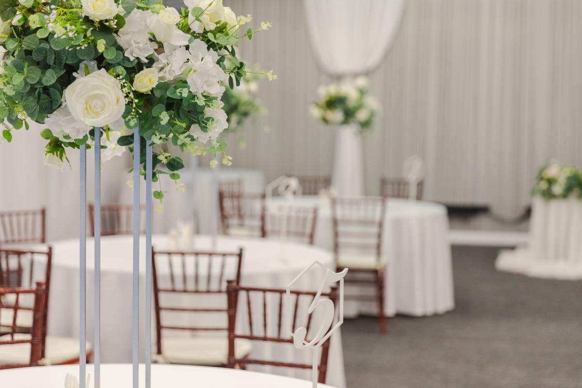 Decorated interior for festive event. Fancy table set for dinner with white flower composition in restaurant, luxury interior background